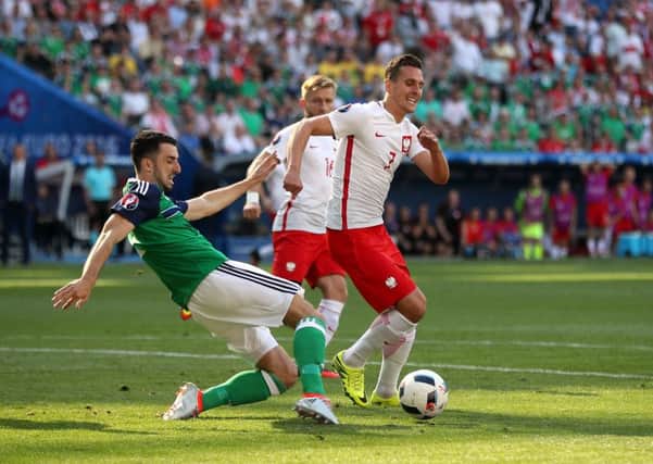 Northern Ireland's Conor McLaughlin (left) and Poland's Arkadiusz Milik battle for the ball. PIC: PA