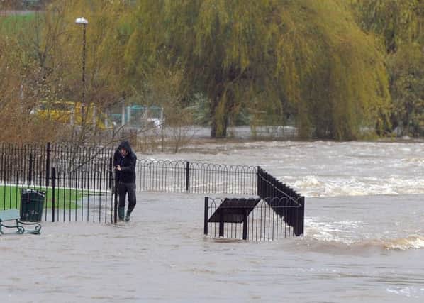 A man holds onto railings as he walks through the flood water in Otley.