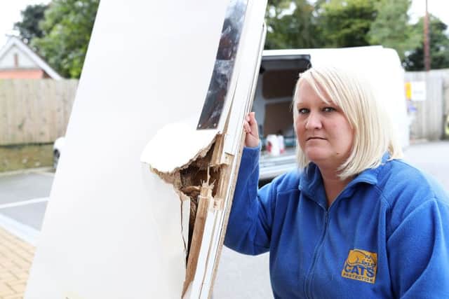 Deputy manager Catherine Hubbard pictured with a door damaged during the raid on Gildersome Cats Protection.