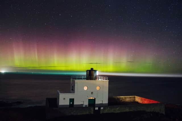 The Northern Lights, or Aurora Borealis appear in the sky over Bamburgh lighthouse at stag Rock in Northumberland. PIC: PA