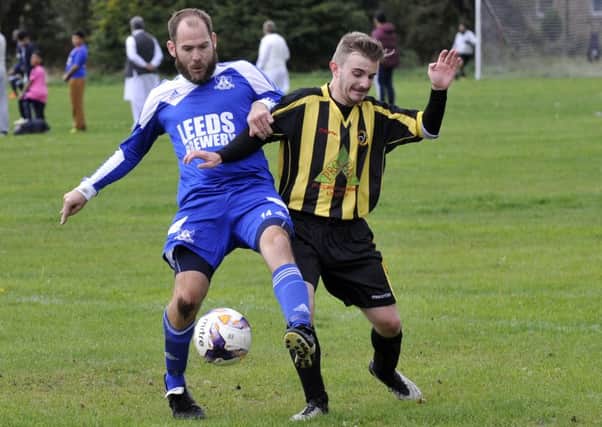Pete Walsh of Leeds City OB wins the ball from James Scurrah of Norristhorpe