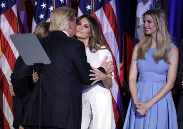 President-elect Donald Trump kisses his wife Melania Trump as his daughter Ivanka Trump watches after giving his acceptance speech during his election night rally.