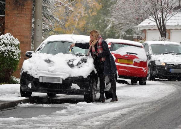 A commuter clears snowfall from her car in Farsley. PIC: Tony Johnson