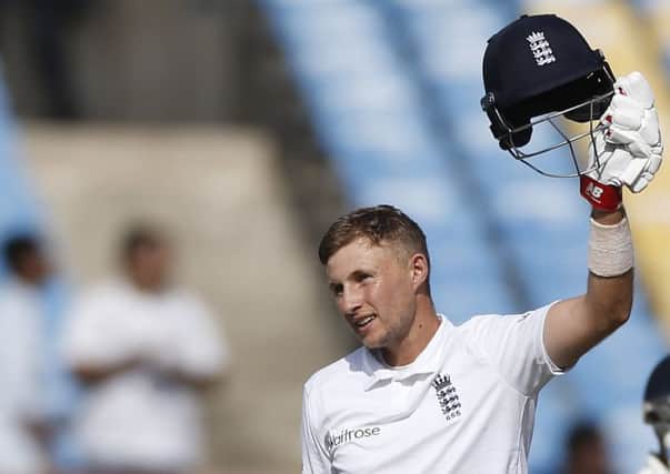 Joe Root raises his helmet after scoring hundred runs during the first day of the first test cricket match between India and England in Rajkot, India, (AP Photo/Rafiq Maqbool)