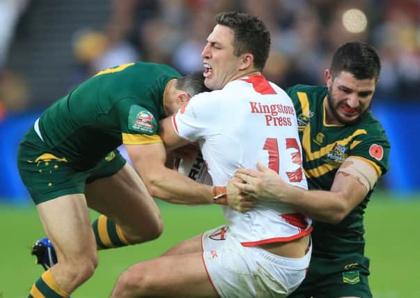 England's Sam Burgess is tackled by Australia's Cooper Cronk (left) and Matt Gillett (right) during the Four Nations match at London Stadium.