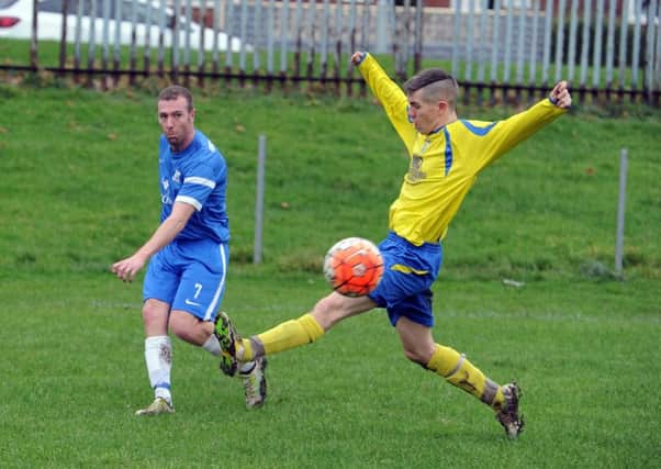 HT Sports' Graham Sides crosses the ball as Seacroft's Gavin Sellers closes in.