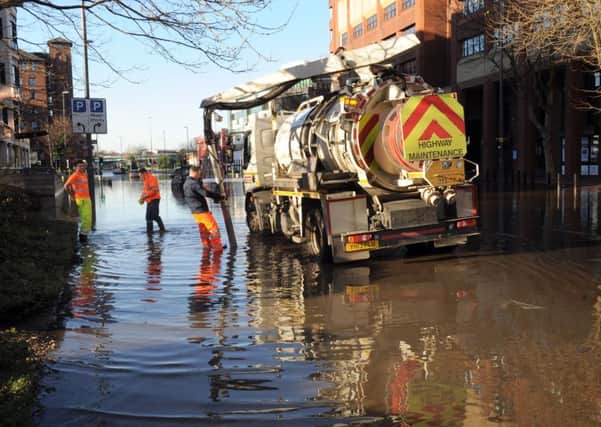 DECEMBER 27, 2015: Workmen try to clear flooded Wellington Street, Leeds.