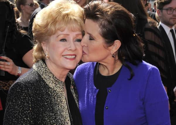 Carrie Fisher kisses her mother, Debbie Reynolds, as they arrive at the Primetime Creative Arts Emmy Awards in Los Angeles in 2011.(AP Photo/Chris Pizzello, File)