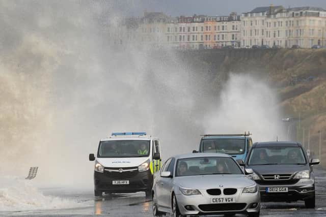 Cars dodge the waves before the road was closed off.