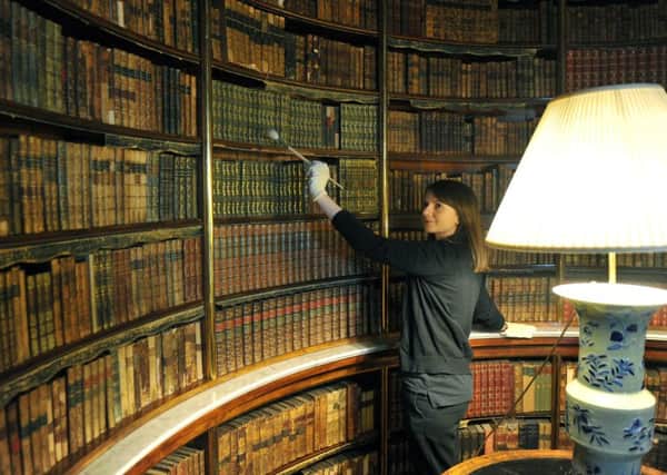 Rachel Curwen, housekeeper at Harewood House cleaning the books in the library.