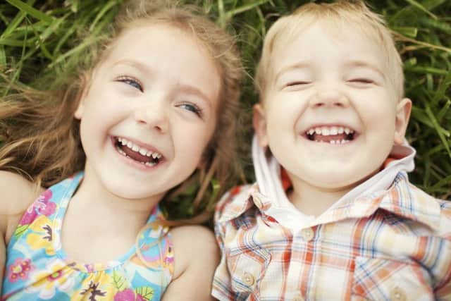 Top view portrait of two happy smiling kids lying on green grass. Cheerful brother and sister laughing together.