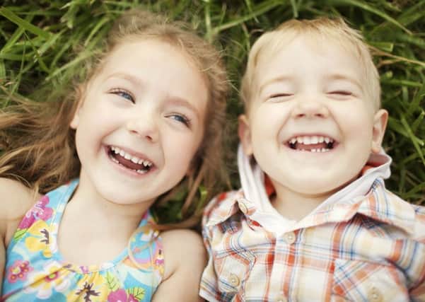 Top view portrait of two happy smiling kids lying on green grass. Cheerful brother and sister laughing together.