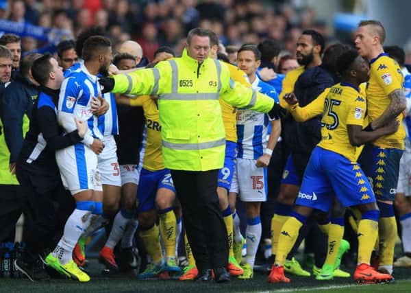 EASE IT BACK A BIT: A steward tries to separate Huddersfield Town and Leeds United players at the John Smith's Stadium on Sunday. Picture: Nigel French/PA