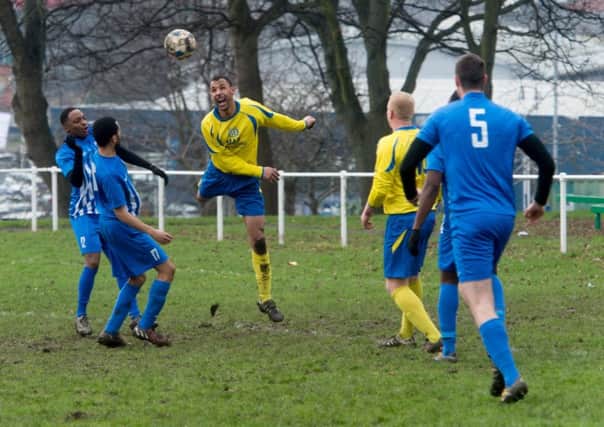 Seacroft WMC's Ryan Harwood heads the ball away as Chapeltown Fforde Grene players move in. PIC: James Hardisty