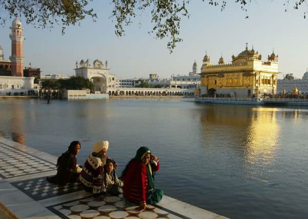 Pilgrims sit at the edge of the moat surrounding the Golden Temple of Amritsar in India's Punjab region. PIC: PA