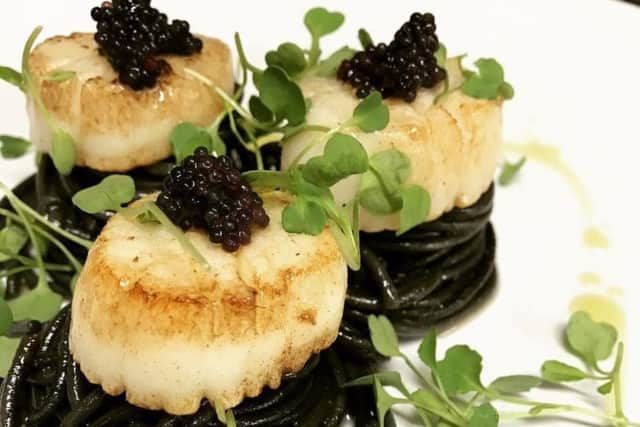 Hand fished scallops on cuttlefish ink spaghetti, garnished with caviar.