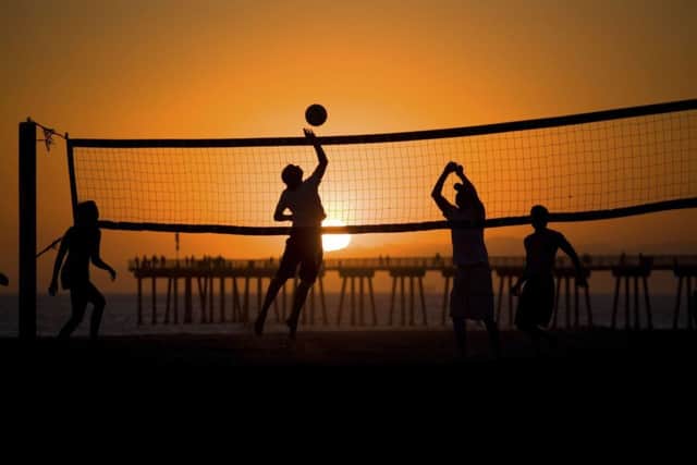 People play beach volleyball during sunset at a beach in LA.  PIC: PA
