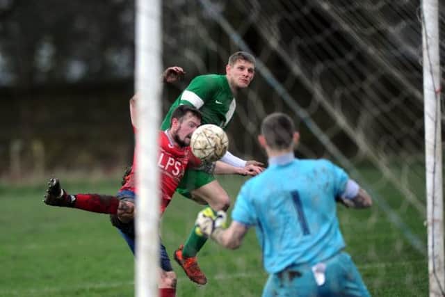 New Pudsey's Dave Thornton gets a header on goal past Bramley's Kristopher Robson. PIC: Jonathan Gawthorpe