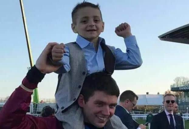 Bradley Lowery is held aloft by Grand National-winning jockey Derek Fox