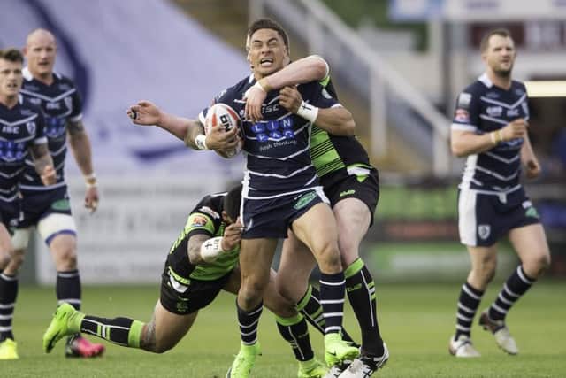 Featherstone's Misi Taulapapa is tackled by Halifax's Mitch Cahalane.