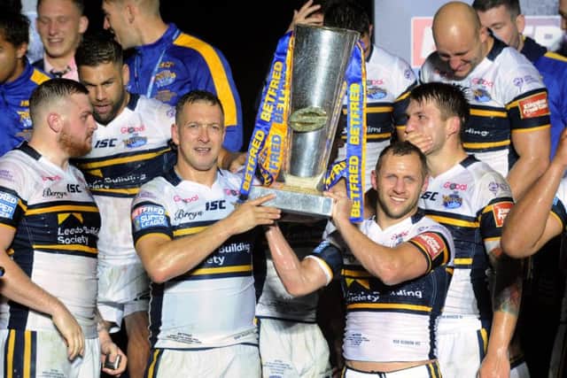 Danny McGuire and Rob Burrow lift the Super League trophy.