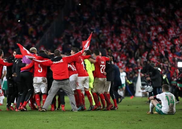 Northern Ireland's Stuart Dallas (right) sits dejected as Switzerland players celebrate after the FIFA World Cup Qualifying second leg match at St Jakob Park, Basel. PIC: Nick Potts/PA Wire