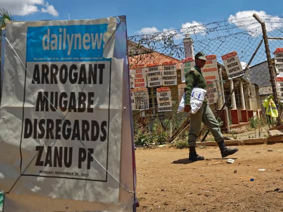 A prison officer walks past a news stand in Harare, Zimbabwe Monday, Nov. 20, 2017. Longtime President Robert Mugabe ignored a midday deadline set by the ruling party to step down or face impeachment proceedings, while Zimbabweans, stunned by his lack of resignation during a national address, vowed more protests to make him leave. (AP Photo/Ben Curtis)