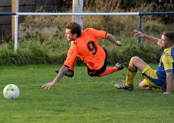 Ryan Barker, of Hall Green United, takes a tumble after being fouled by Swillington's Sean O'Neill. PIC: Steve Riding