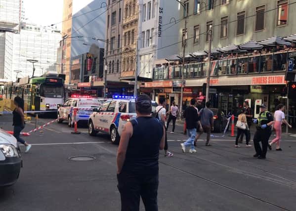 Pedestrians walk past as police and emergency services attend the scene of an incident involving a vehicle and pedestrians in Melbourne.