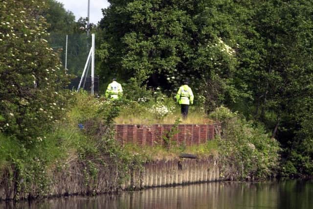 Police officers walk along the river bank in Kirkstall near to where Ian Webster's body was found in June 2002.
