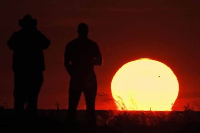 Spectators at Edgewater Park in Cleveland watch the sun set as the planet Venus crosses the upper right portion of the star, Tuesday, June 5, 2012. The next transit of Venus won't be for another 105 years. (AP Photo/Mark Duncan)