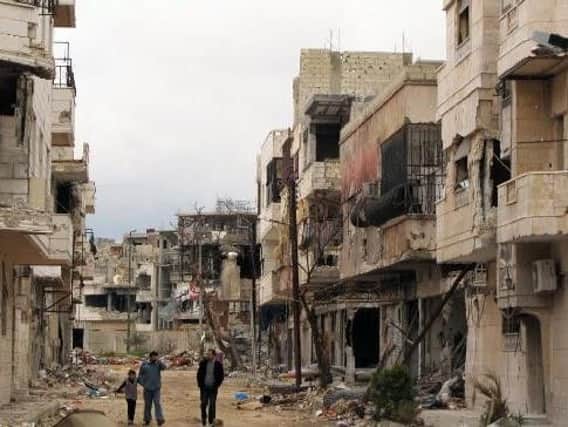Residents walk between destroyed buildings in Syria (AP photo).