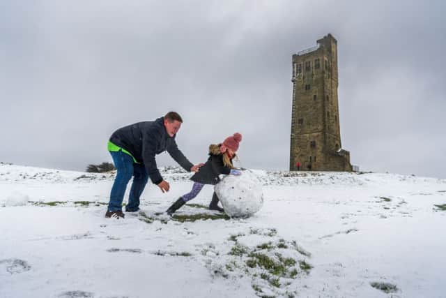 Date: 21st January 2018.
Picture James Hardisty.
Heavy snow fall over part of Yorkshire, pictured Edward Beardsall, with daughter Amelie, aged 5, having fun rolling a snow ball at Castle Hill, Huddersfield, West Yorkshire.