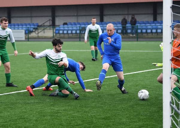 Sporting 
Pudsey's Connor Ward scores past Woodcock's Danny Alcock in his side's 10-0 Leeds Combination Division One victory. PIC: Jonathan Gawthorpe