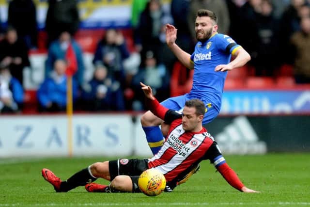 Leeds United's Stuart Dallas is tackled by Sheffield United's Billy Sharp.