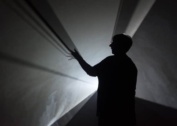 A visitor looks at Anthony McCalls Doubling Back, 2003.Inset, Anthony McCall. PIC: Guzelian