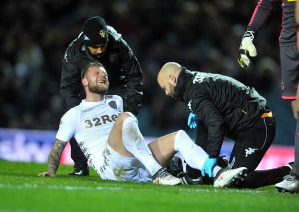 PAIN: Leeds United captain Liam Cooper receives treatment before hobbling off injured in the first half. Picture by Tony Johnson.
