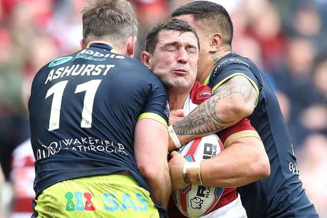 Wigan Warriors Ben Flower is tackled by Wakefield Trinity's Matty Ashurst (left) and Tinirau Arona (right).