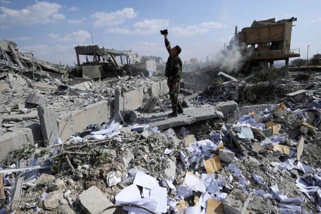 devastation: A Syrian soldier films the damage of the Syrian Scientific Research Centre which was attacked by US, British and French military strikes to punish President Bashar Assad for a suspected chemical attack.