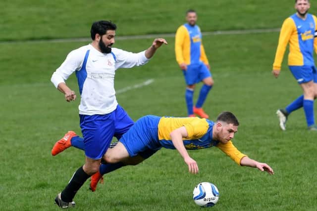 Hope Inn Whites goalscorer Stephen Crawford takes a tumble under pressure from Zaheer Ahmed of Leeds City Rovers during Sunday's Jubilee Premier encounter. PIC: Jonathan Gawthorpe