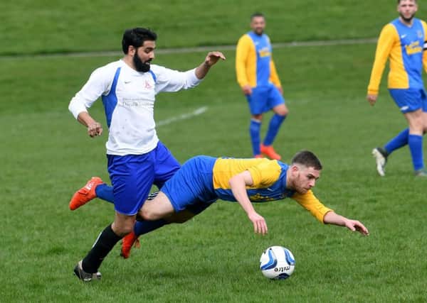 Hope Inn Whites goalscorer Stephen Crawford takes a tumble under pressure from Zaheer Ahmed of Leeds City Rovers during Sunday's Jubilee Premier encounter. PIC: Jonathan Gawthorpe