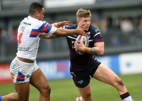 Liam Sutcliffe is tackled by Wakefield Trinity's Reece Lyne.