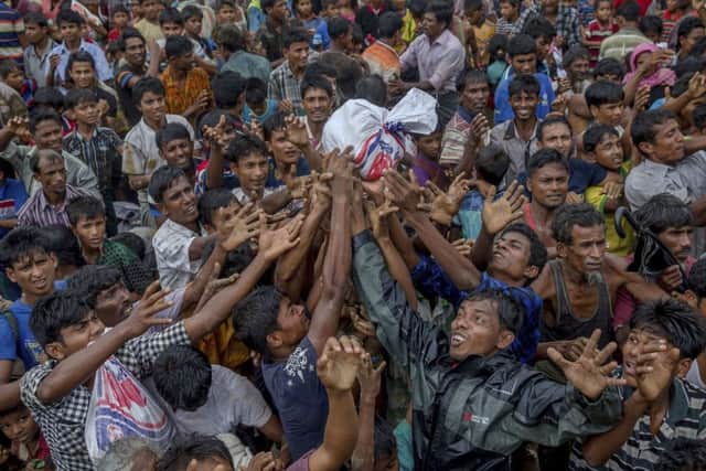 Rohingya Muslims, who crossed over from Myanmar into Bangladesh, stretch their arms out to collect food items distributed by aid agencies near Balukhali refugee camp, Bangladesh, Monday, Sept. 18, 2017.  (AP Photo/Dar Yasin)