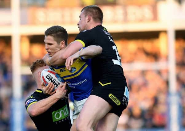 Matt Parcell is tackled by Warrington's Harvey Livett and Mike Cooper.