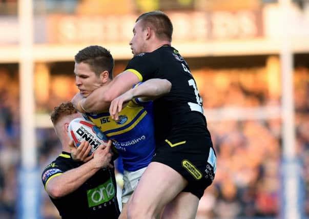 Matt Parcell is tackled by Warrington's Harvey Livett and Mike Cooper.