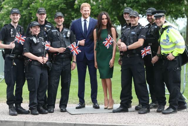 Police officers pose with the Madame Tussauds' wax figures of Prince Harry and Meghan Markle as they are paraded along the Long Walk in Windsor ahead of the royal wedding this weekend. PIC: PA