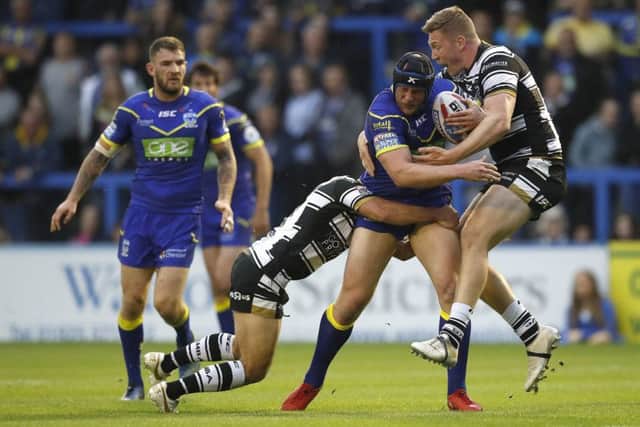 Warrington Wolves' Chris Hill is tackled by Hull FC's Danny Houghton (left) and Chris Green (right).