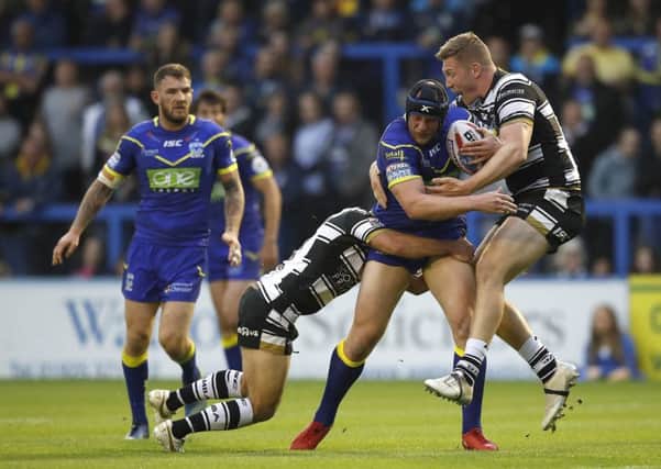 Warrington Wolves' Chris Hill is tackled by Hull FC's Danny Houghton (left) and Chris Green (right).